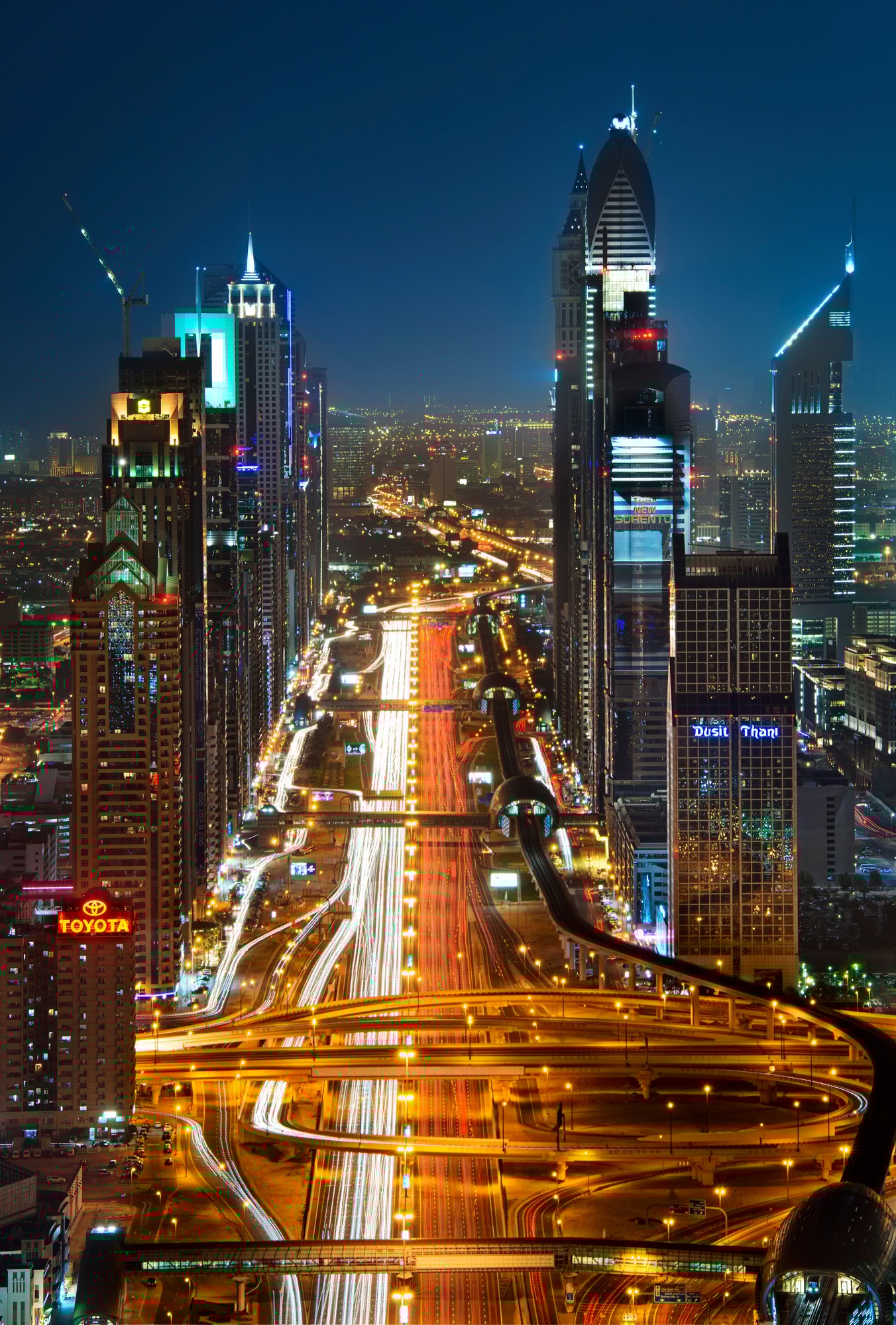 Cityscape with skyscrapers and illuminated road in Dubai, United Arab Emirates at dusk.